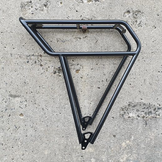 A Tubus Fat rack in black powdercoated steel hangs from a concrete wall