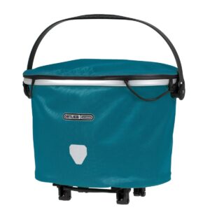 An Ortlieb Up-Town Rack City handlebar bag in the form of a basket is shown in a blue waterproof material with a plastic handle
