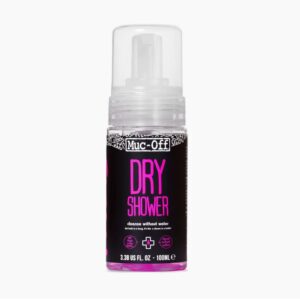 A small aerosol bottle of Muc-Off Dry Shower is shown in black with a white clear cap