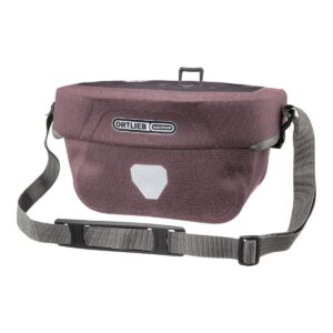 an Ortlieb Ultimate Six Urban handlebar mounting bag in an Ash Rose coloured Cordura fabric with a grey shoulder strap visible