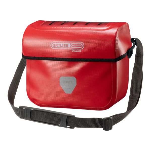 An Ortlieb Ultimate Original handlebar bag is shown in retro cheery red waterproof material with a black shoulder strap and a reflective panel on the front