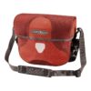 an Orlieb Ultimate Six Plus handlebar bag is shown in waterproof Cordura material in a dual red colourway with grey shoulder strap and stitching