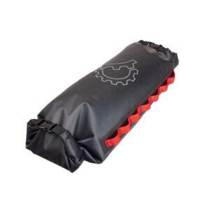A Revelate Saltyroll bikepacking drybag designed for mounting on a handlebar carrying system is shown in a black waterproof material with two ends with roll-down closures and red daisy chain webbing down the long side