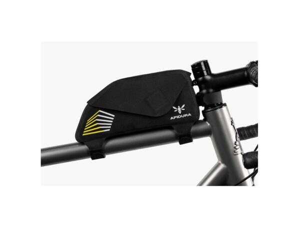 An Apidura Racing Top Tube Pack 1L is shown in a black waterproof laminate material, affixed to the stem & top tube of a bicycle