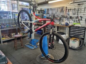 A Specialized Stumpjumper dual suspension mountain bike is shown in a workstand in the workshop having an Essential Service performed on it
