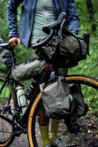 A bike loaded up with Ortlieb bikepacking bags is shown where all the bags are in the new Sand colourway from Ortlieb that is launching in 2024 mid year